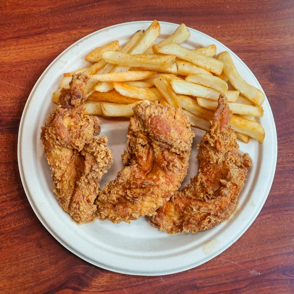Three crispy fried chicken pieces and a pile of seasoned french fries on a white plate.
